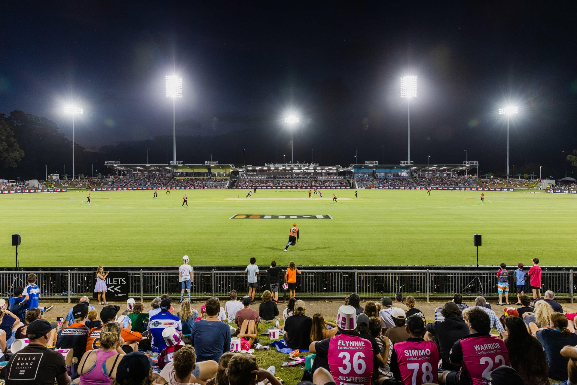 Stadium field at night, with BBL being played and the grandstands in the background